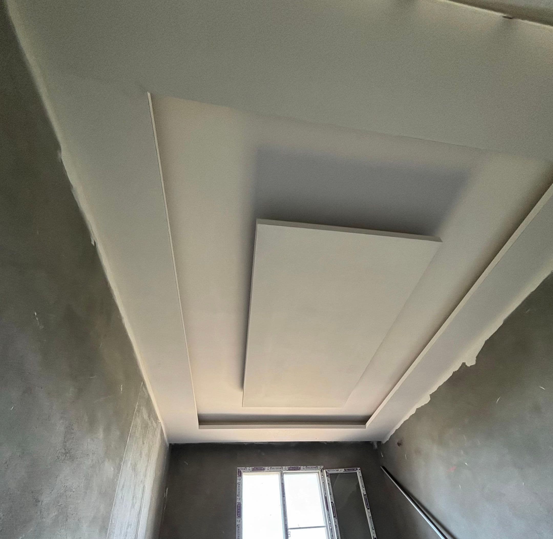Alçıpan asma tavan yapım aşamasında; ortada yuvarlak aydınlatma kaidesi, iskele üzerinde çalışma alanı.